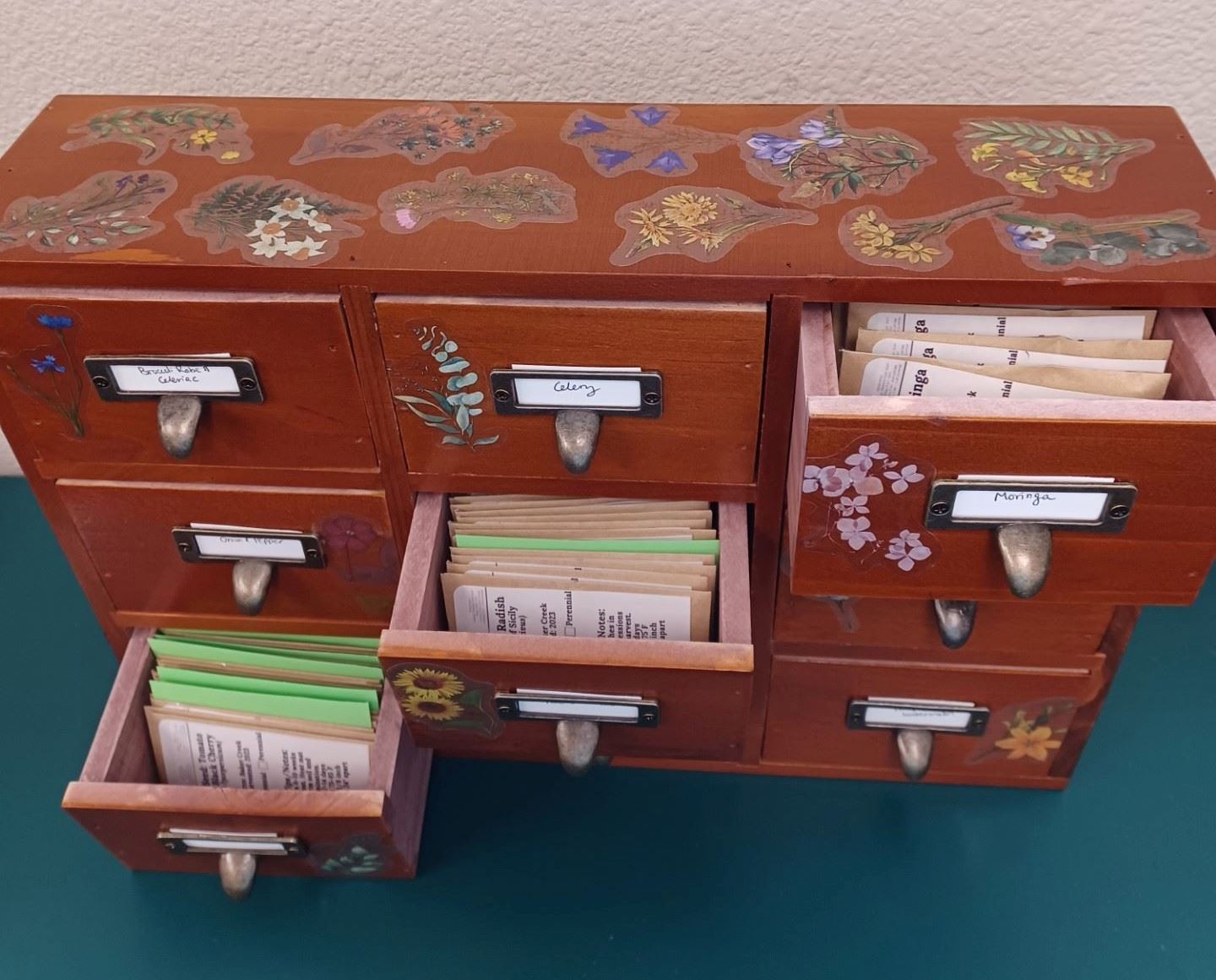 Wooden card Catalog with flower stickers and open drawers with seed packets and green dividers